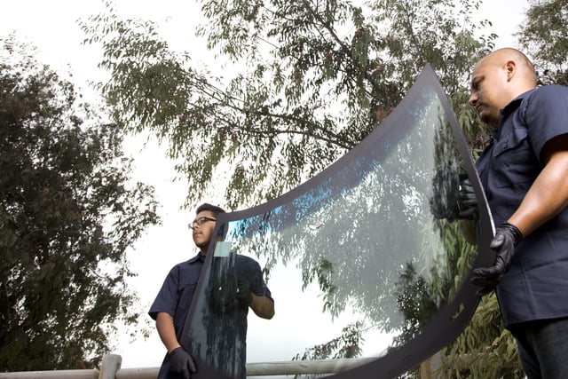 repair men holding replacement car windshield